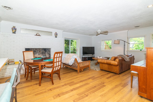 living room with brick wall, light wood-type flooring, a fireplace, and crown molding