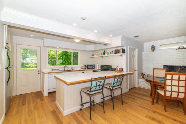 kitchen featuring a breakfast bar area, white cabinets, light hardwood / wood-style floors, and white dishwasher