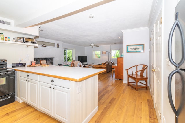 kitchen with a brick fireplace, black appliances, light hardwood / wood-style flooring, and kitchen peninsula