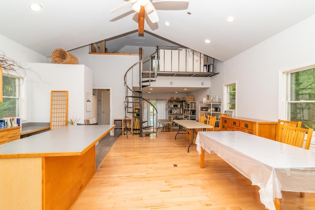 dining room featuring a high ceiling, ceiling fan, a wealth of natural light, and light wood-type flooring