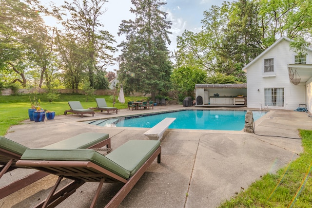 view of pool with a diving board, a patio area, and a lawn