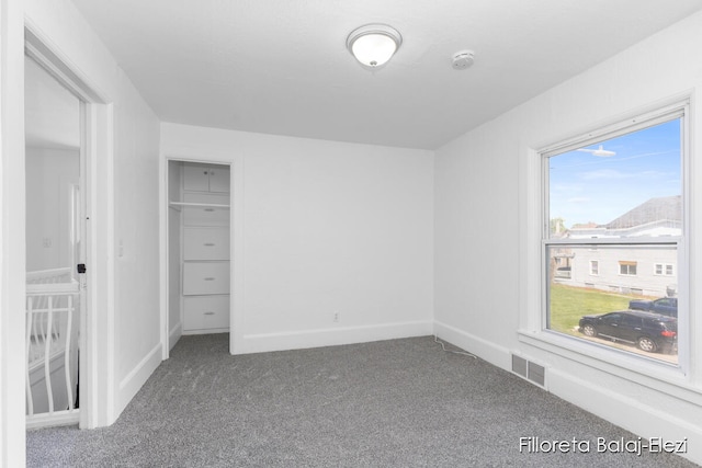 unfurnished bedroom with multiple windows and dark colored carpet