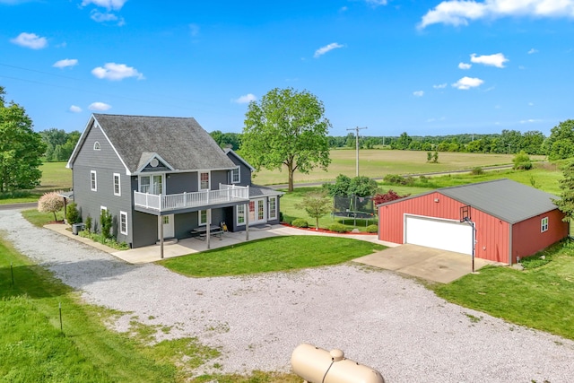 view of front facade with an outbuilding, a front lawn, a trampoline, gravel driveway, and a patio area