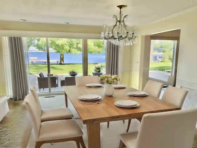 dining room featuring a water view, ornamental molding, and a notable chandelier