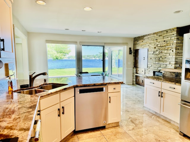 kitchen with light stone countertops, stainless steel appliances, sink, and white cabinets