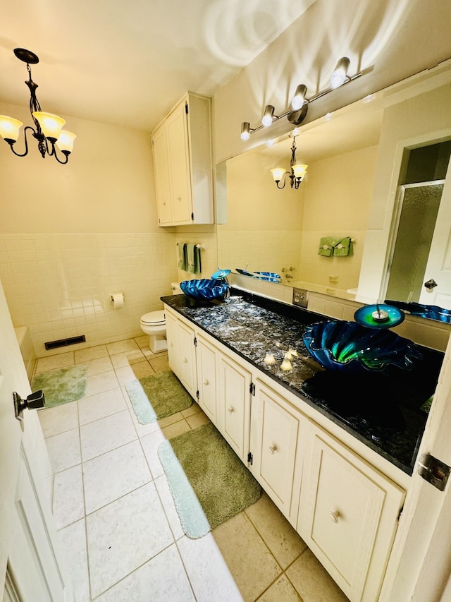 bathroom featuring tile patterned floors, toilet, an inviting chandelier, tile walls, and vanity