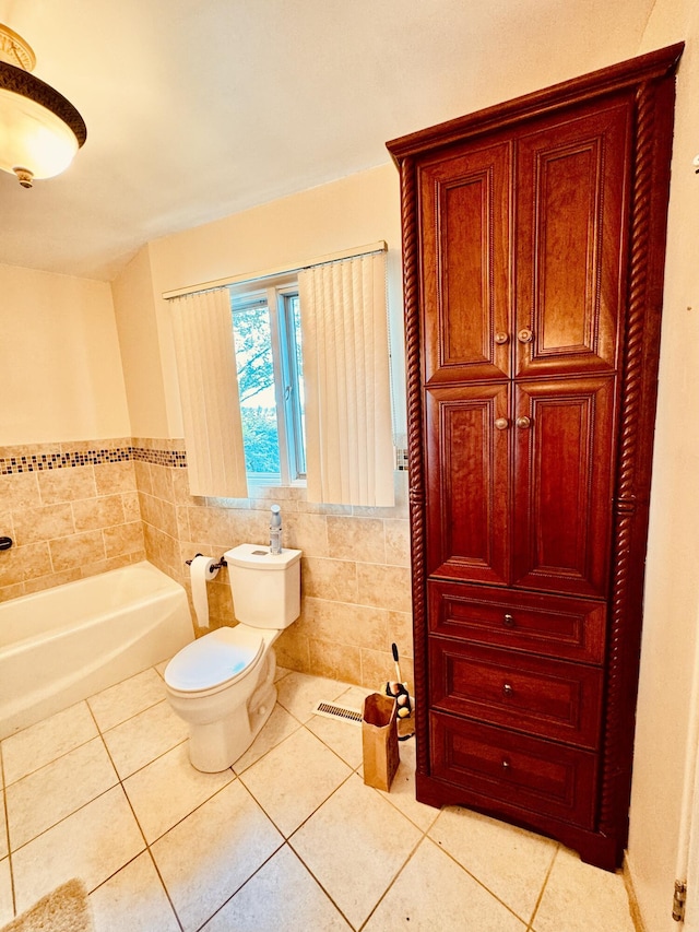 bathroom with tile walls, a tub to relax in, tile patterned floors, and toilet