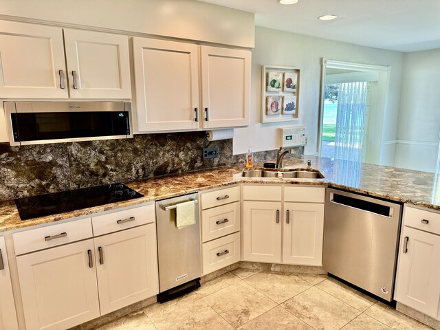 kitchen with stainless steel appliances, light stone countertops, sink, and white cabinets