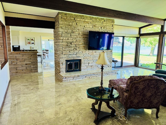 living room featuring a fireplace, beam ceiling, and a wealth of natural light