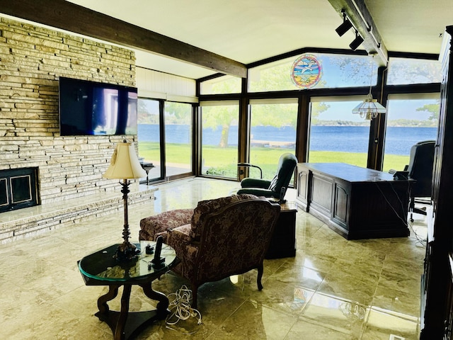 living room with a fireplace, plenty of natural light, lofted ceiling with beams, and a water view