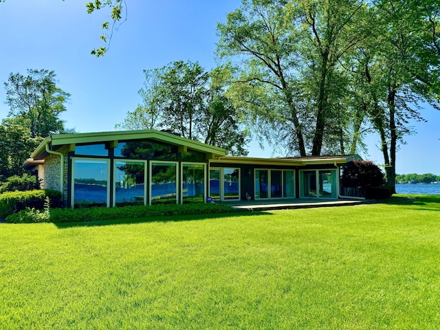 back of property with a water view and a yard