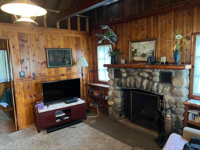 living room featuring a stone fireplace, wooden walls, hardwood / wood-style floors, and beam ceiling