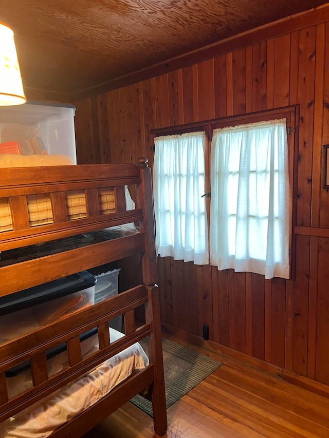 bedroom with wood walls, hardwood / wood-style floors, and multiple windows