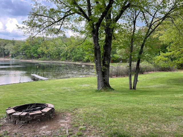 view of yard featuring a dock, a water view, and a fire pit