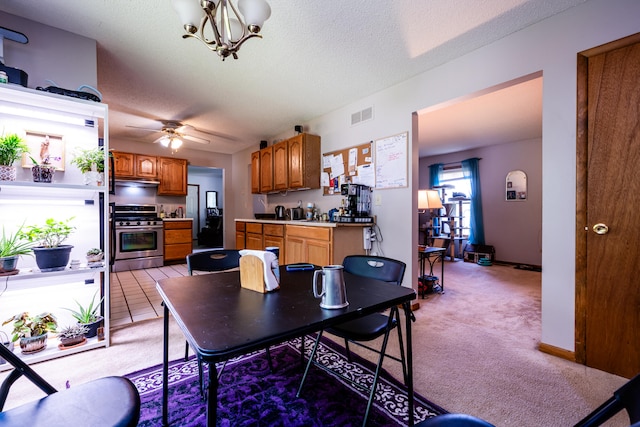 dining area with light carpet, a textured ceiling, and ceiling fan with notable chandelier