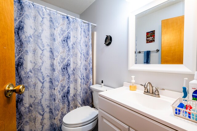 bathroom with a shower with shower curtain, vanity, toilet, and a textured ceiling