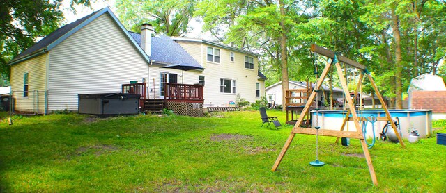 rear view of house with a lawn and a swimming pool with hot tub