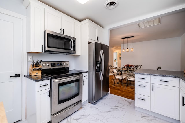 kitchen with stainless steel appliances, dark stone countertops, white cabinets, light tile floors, and pendant lighting