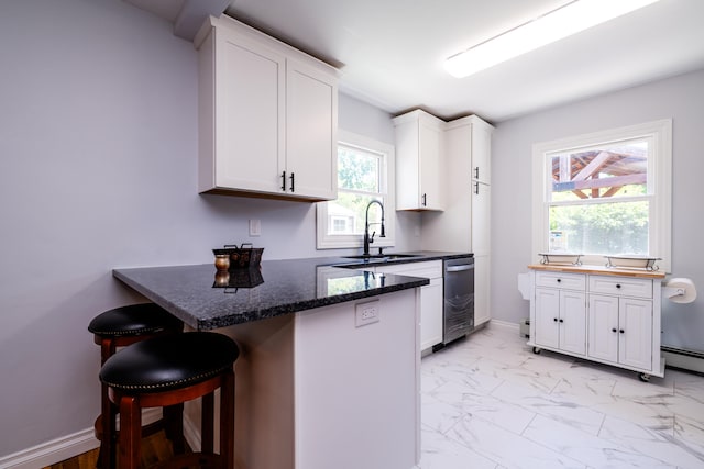 kitchen featuring dark stone counters, a breakfast bar area, white cabinetry, sink, and light tile floors