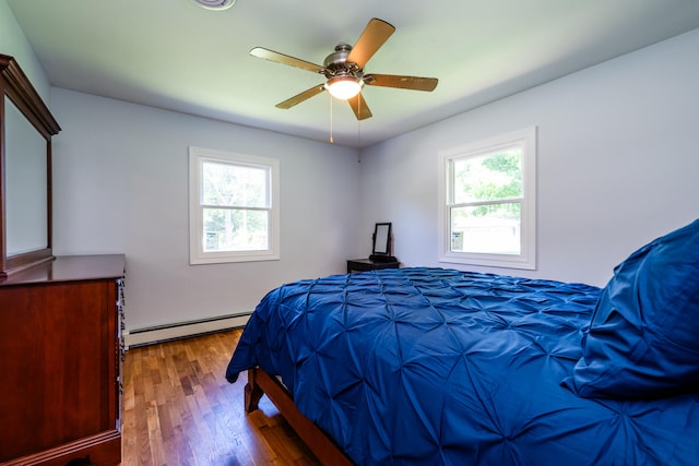 bedroom with dark hardwood / wood-style floors, ceiling fan, multiple windows, and baseboard heating