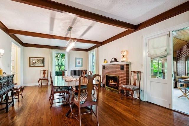 dining area featuring a fireplace, a textured ceiling, dark hardwood / wood-style flooring, and a wealth of natural light