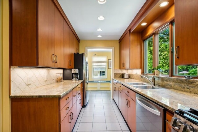 kitchen with light stone counters, light tile patterned flooring, sink, and stainless steel appliances