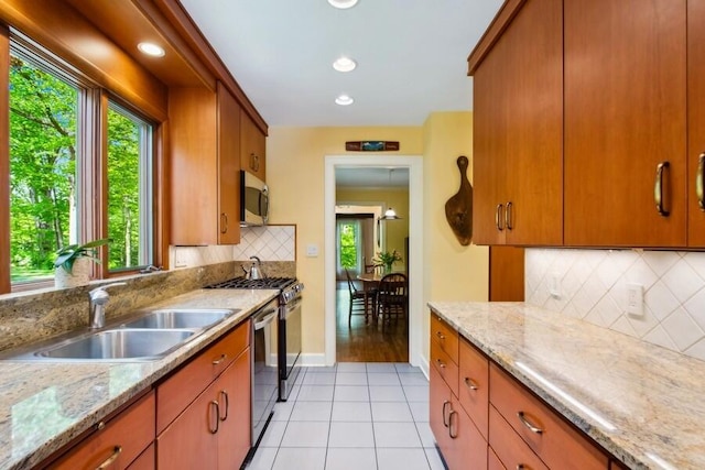 kitchen featuring light stone countertops, sink, stainless steel appliances, tasteful backsplash, and light tile patterned floors