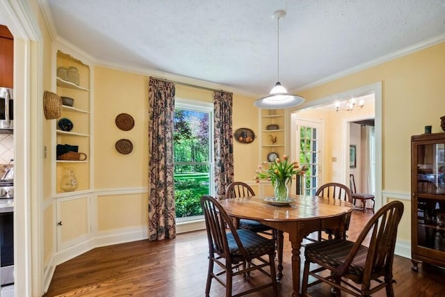 dining room with built in shelves, dark hardwood / wood-style flooring, a textured ceiling, and ornamental molding