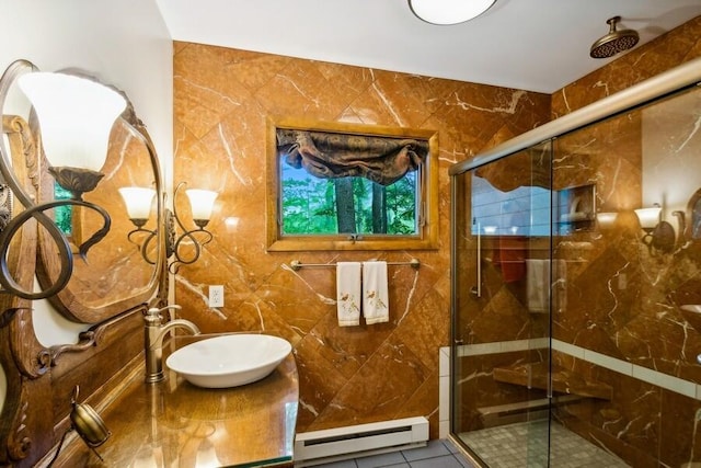 bathroom with tile patterned floors, sink, a shower with shower door, and baseboard heating