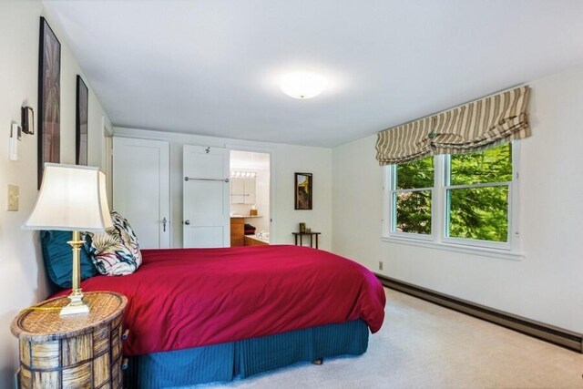 bedroom with ensuite bathroom, carpet floors, and a baseboard radiator