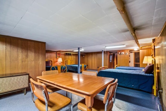 carpeted dining space with wooden walls