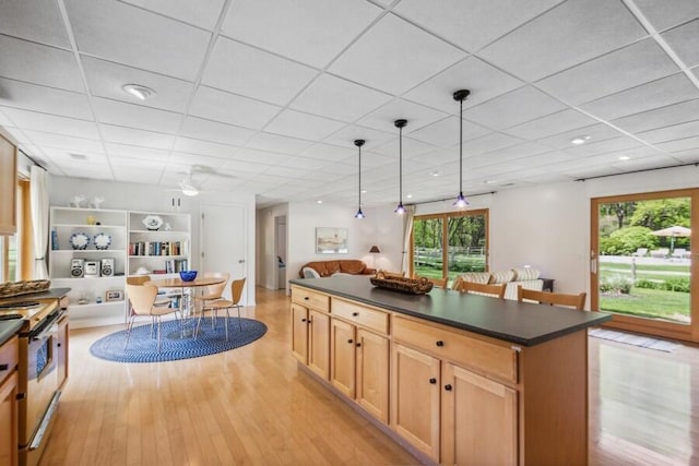 kitchen with ceiling fan, a drop ceiling, stainless steel range oven, light hardwood / wood-style floors, and decorative light fixtures