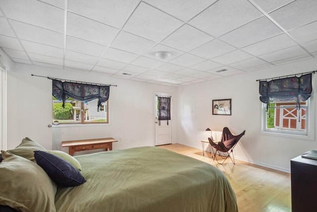 bedroom featuring a drop ceiling and light hardwood / wood-style flooring