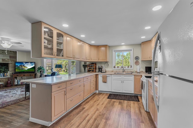 kitchen featuring light wood-type flooring, sink, white appliances, and kitchen peninsula