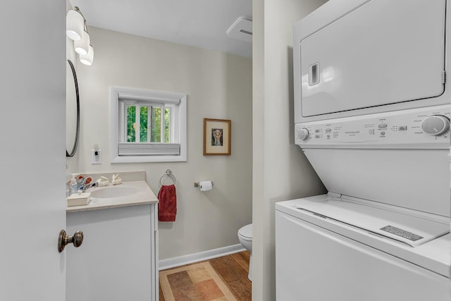 laundry area featuring stacked washer / drying machine and sink