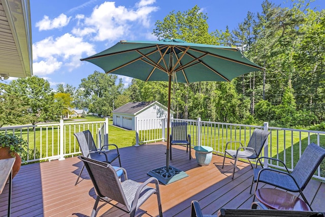 wooden deck with a garage, a yard, and an outbuilding