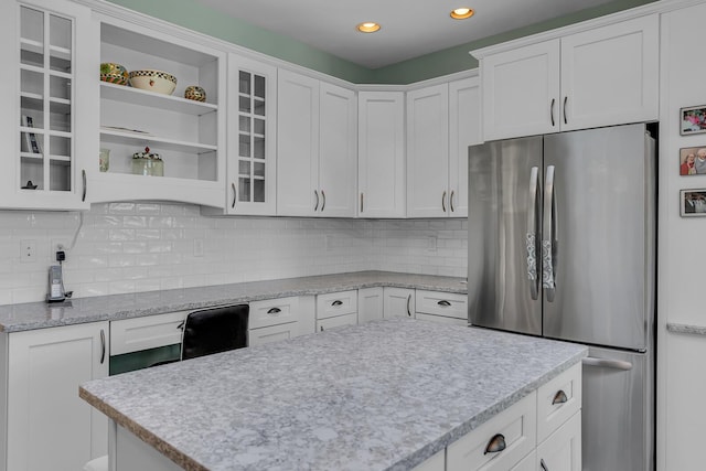 kitchen with tasteful backsplash, white cabinetry, and stainless steel refrigerator