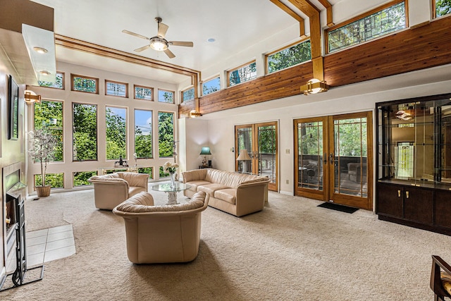 living room with light carpet, french doors, a towering ceiling, and plenty of natural light