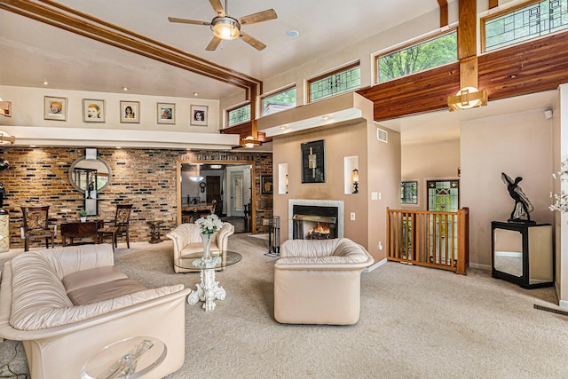 living room featuring ceiling fan, a towering ceiling, a fireplace, light colored carpet, and brick wall