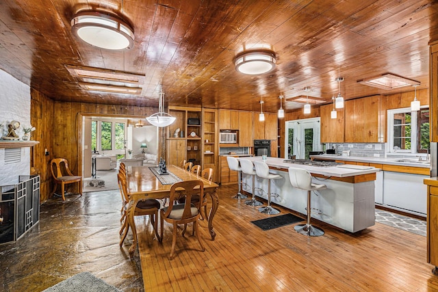 dining room with hardwood / wood-style flooring, wood ceiling, sink, and a brick fireplace