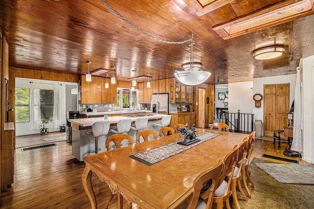 dining area featuring a skylight, dark hardwood / wood-style floors, wood walls, and wood ceiling