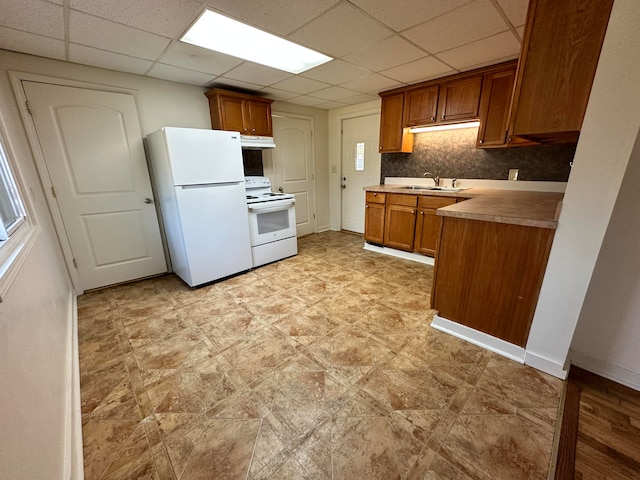 kitchen featuring white appliances, sink, tasteful backsplash, and a drop ceiling