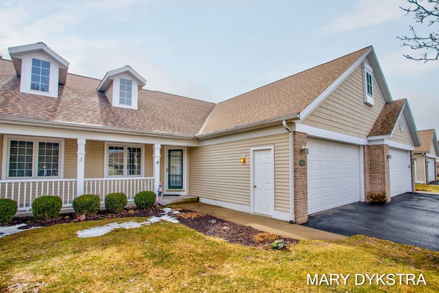 view of front of property featuring covered porch, brick siding, a shingled roof, and aphalt driveway