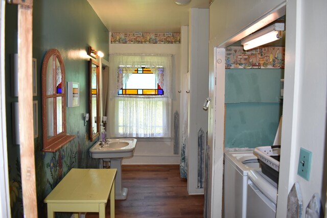 bathroom with washing machine and clothes dryer, sink, and wood-type flooring