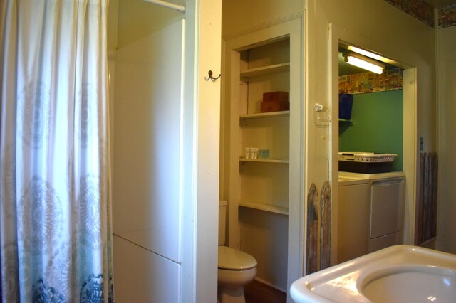 bathroom featuring sink, toilet, and washing machine and clothes dryer