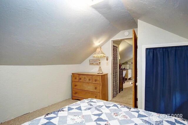 carpeted bedroom featuring a textured ceiling and vaulted ceiling