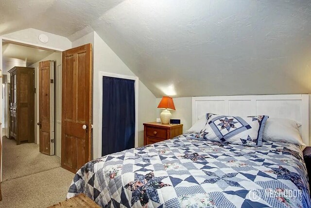 bedroom with a textured ceiling, light colored carpet, and lofted ceiling