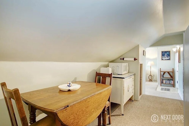 dining space with light colored carpet and vaulted ceiling