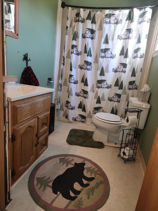 bathroom with tile patterned flooring, vanity, toilet, and walk in shower