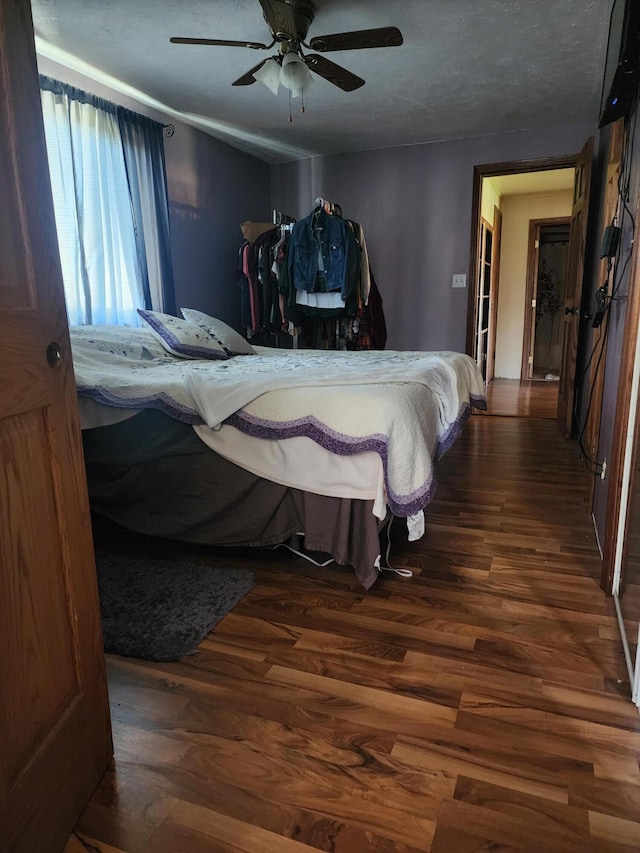 bedroom with a textured ceiling, dark hardwood / wood-style flooring, and ceiling fan